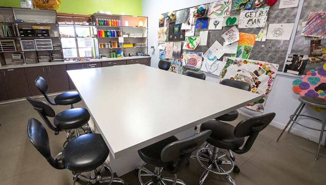 Art therapy space with table, stools, and colorful supplies
