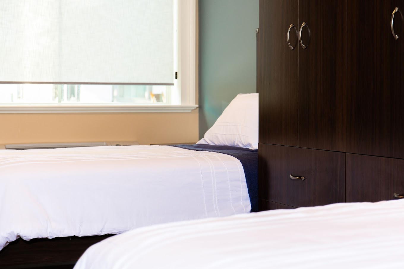 Dorm-style bedroom featuring two single beds and a dresser.