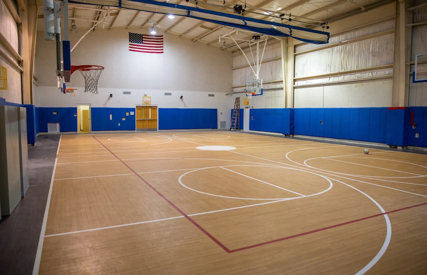 Indoor basketball court with hoops and blue wall padding