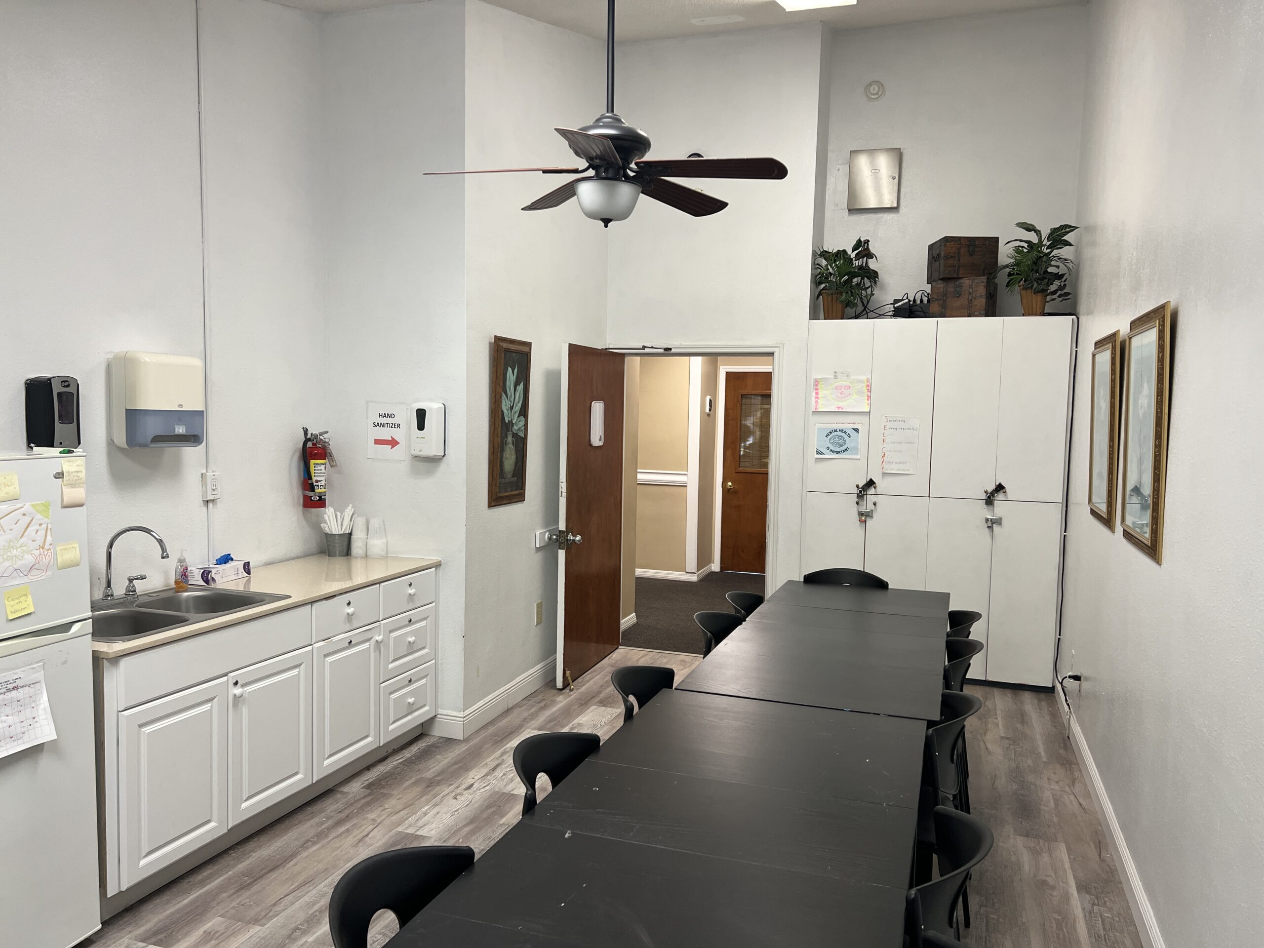 Clean dining area with long black tables and a kitchenette