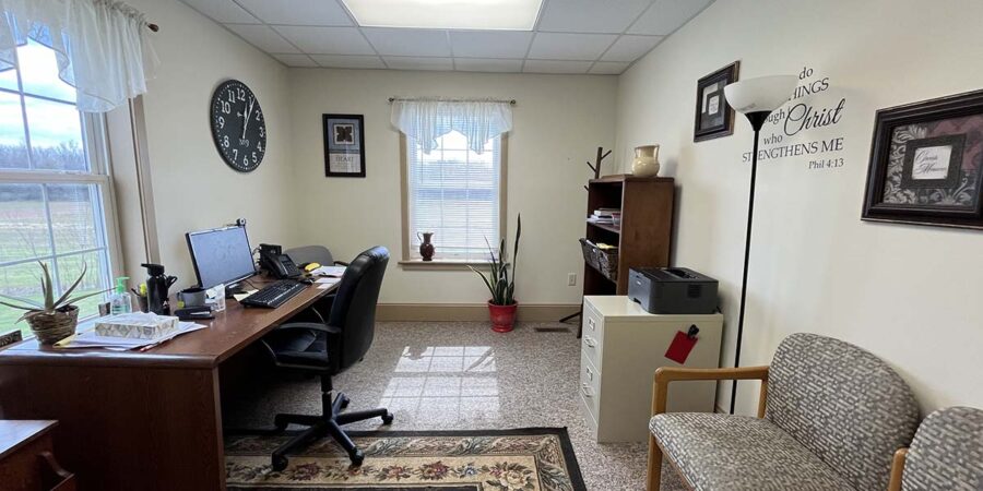 Office desk beside scripture wall and window