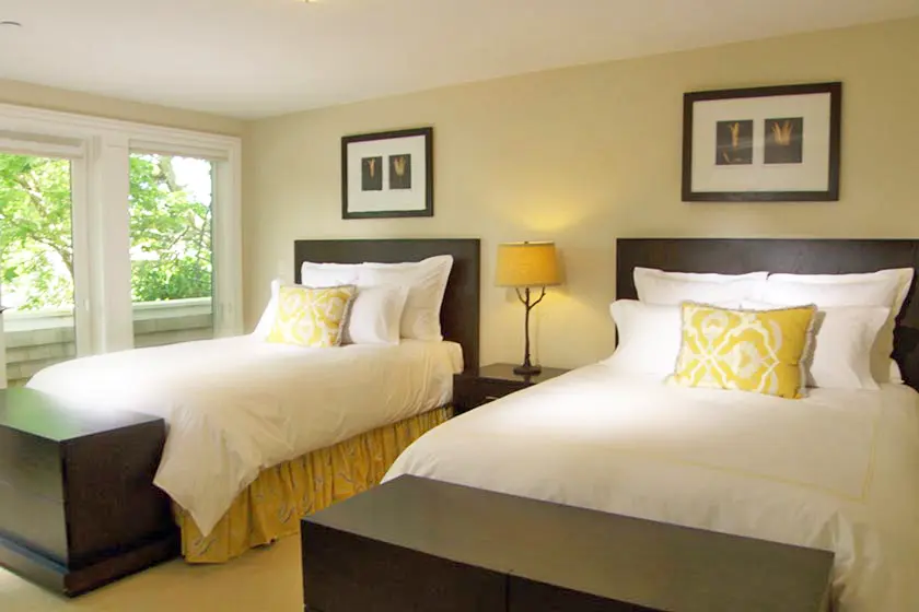 Two beds with yellow pillows in a bright room