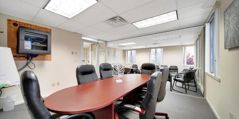 A modern boardroom featuring a large conference table surrounded by comfortable chairs, ideal for meetings and group discussions.