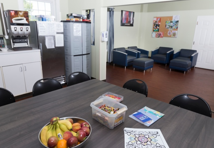 Table with fruit, crayons, and lounge chairs in common room