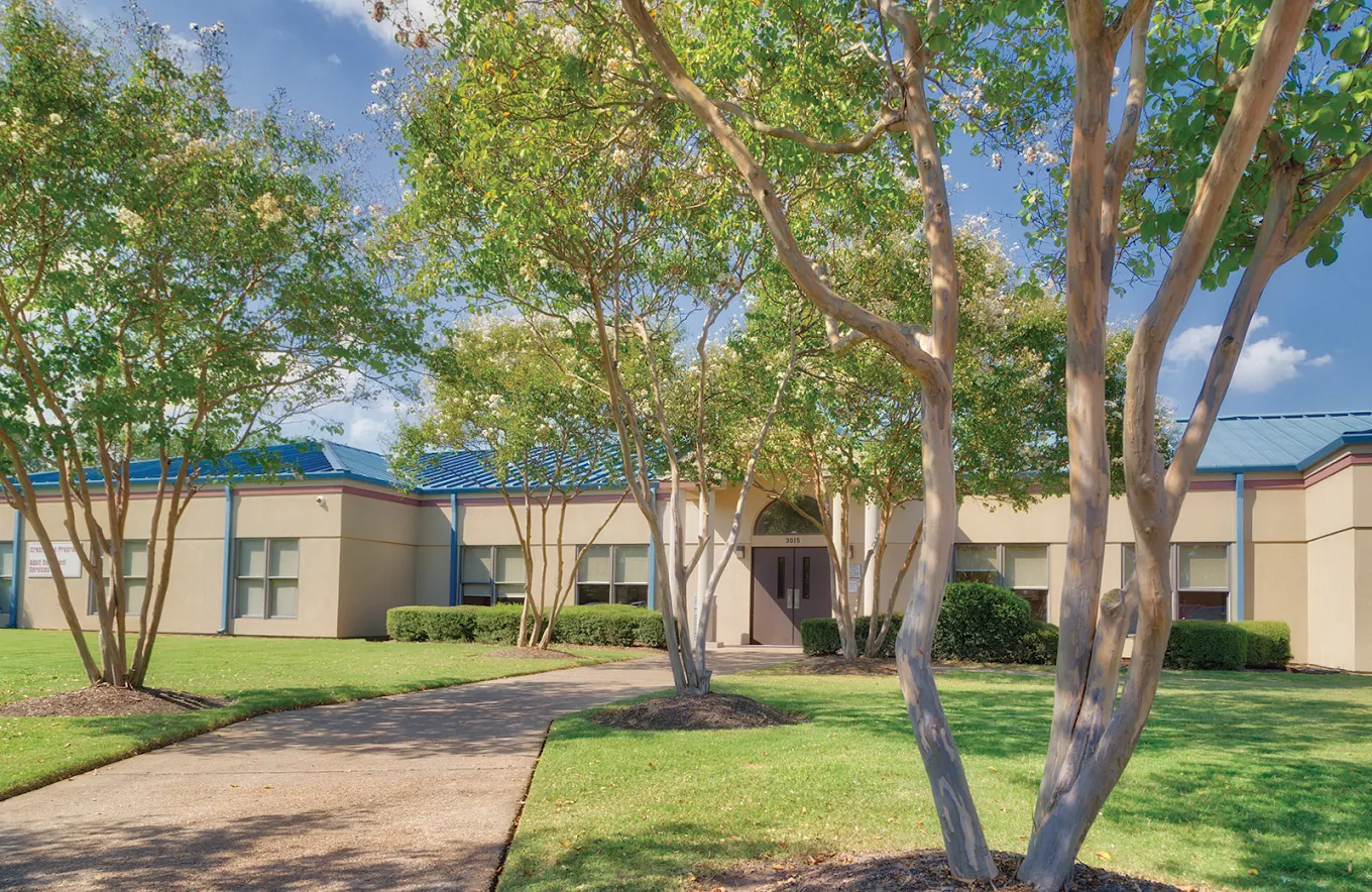 Facility entrance with landscaped walkway and trees