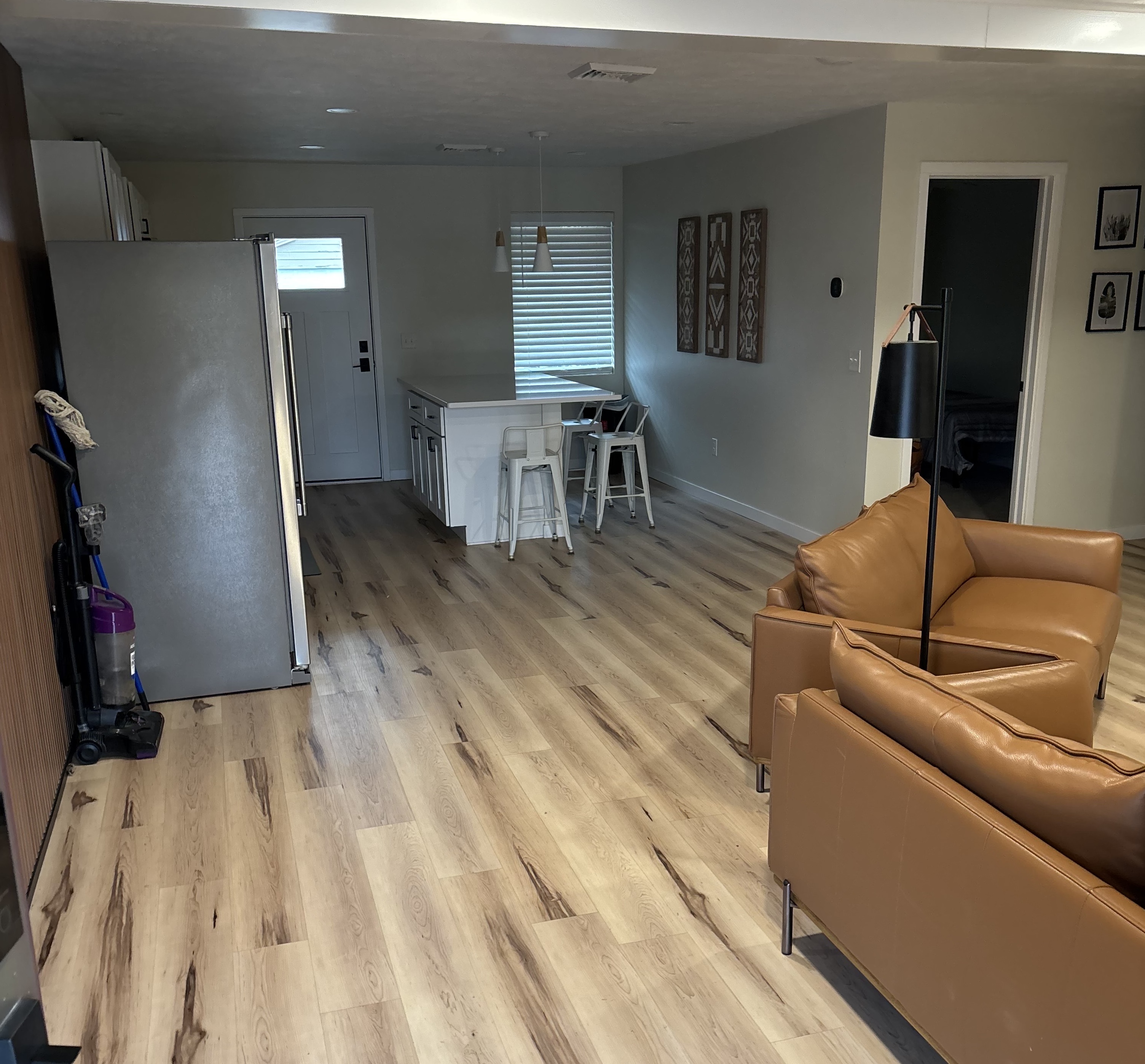 Open kitchen-living space with island, fridge, and tan armchairs.
