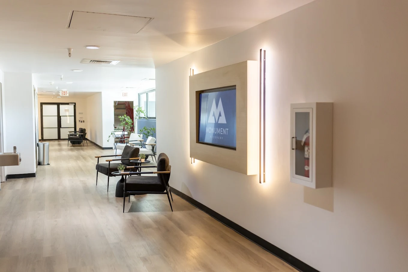 Bright hallway with seating, wall art, and wood flooring