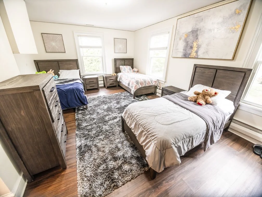 Shared bedroom with three beds and large windows