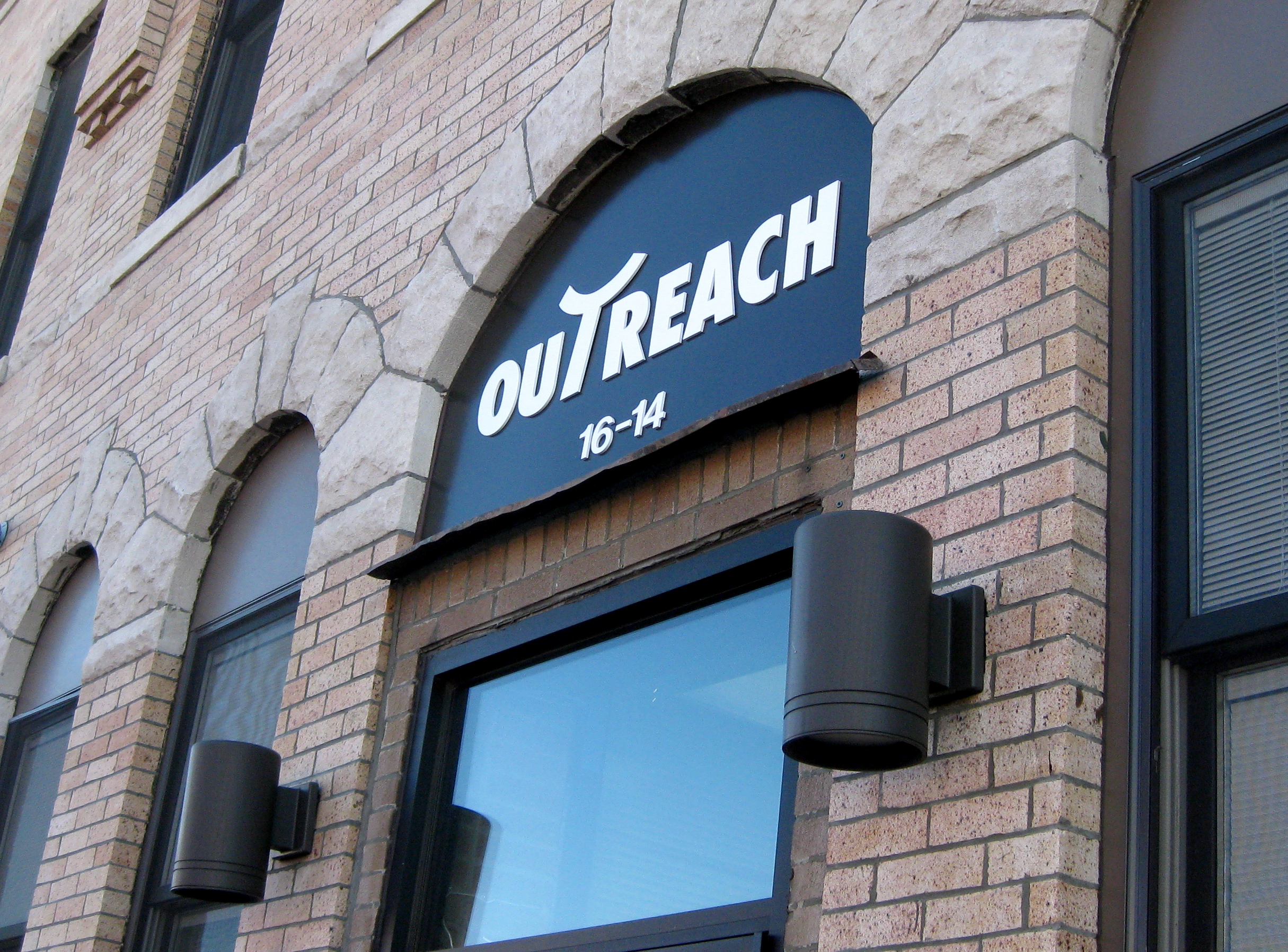 Outreach House entrance sign on historic brick building facade.