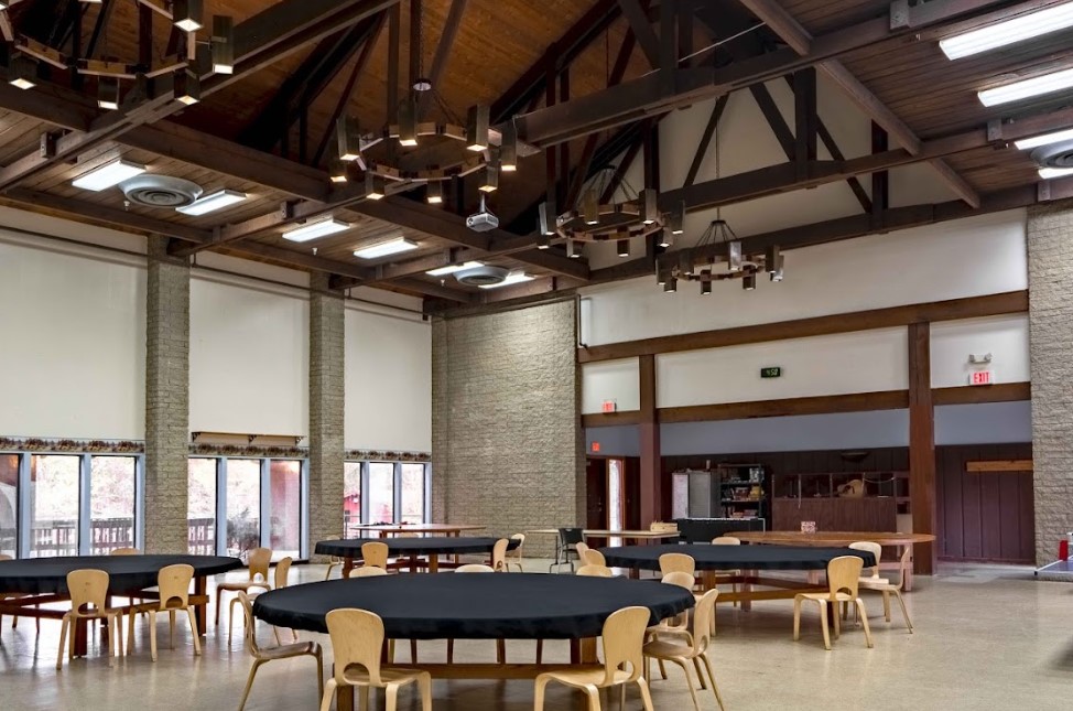A high-ceiling dining hall with round tables and rustic chandeliers