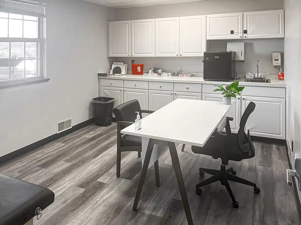 Medical room with white cabinets, desk, and seating area