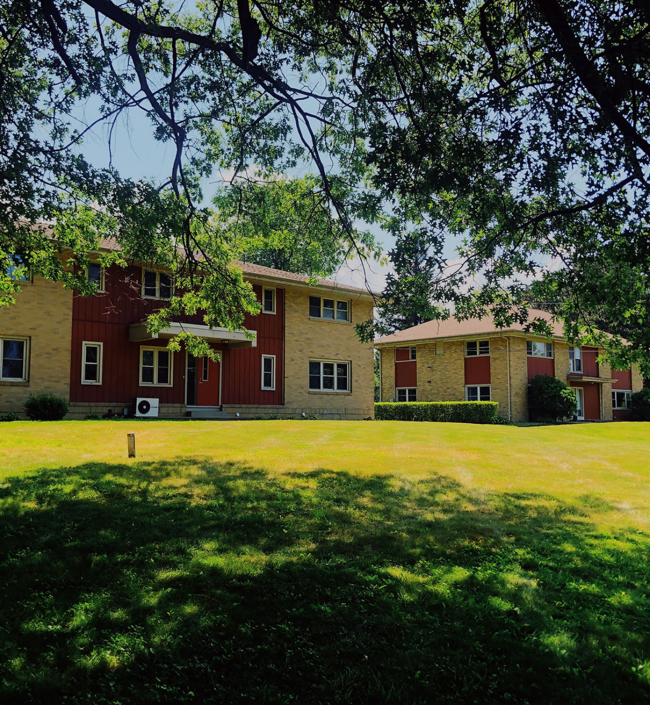 Two brick residential buildings on green lawn
