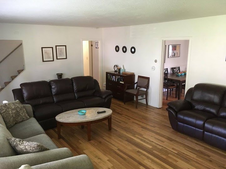 Living room with leather couches and wooden flooring