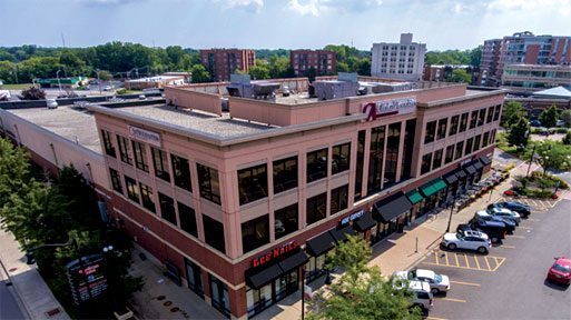 A large two-story commercial building with parking and businesses.