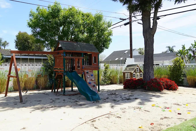 Play area with slide, swings, and sandbox for kids