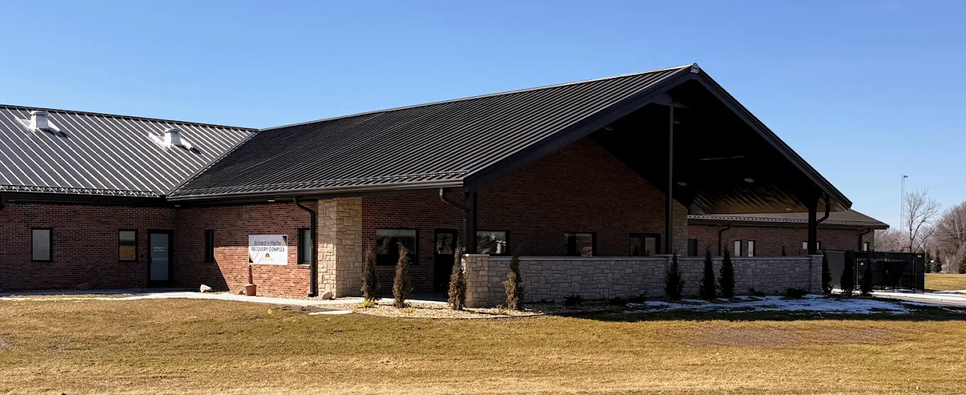 Corner view of brick facility with black metal roof