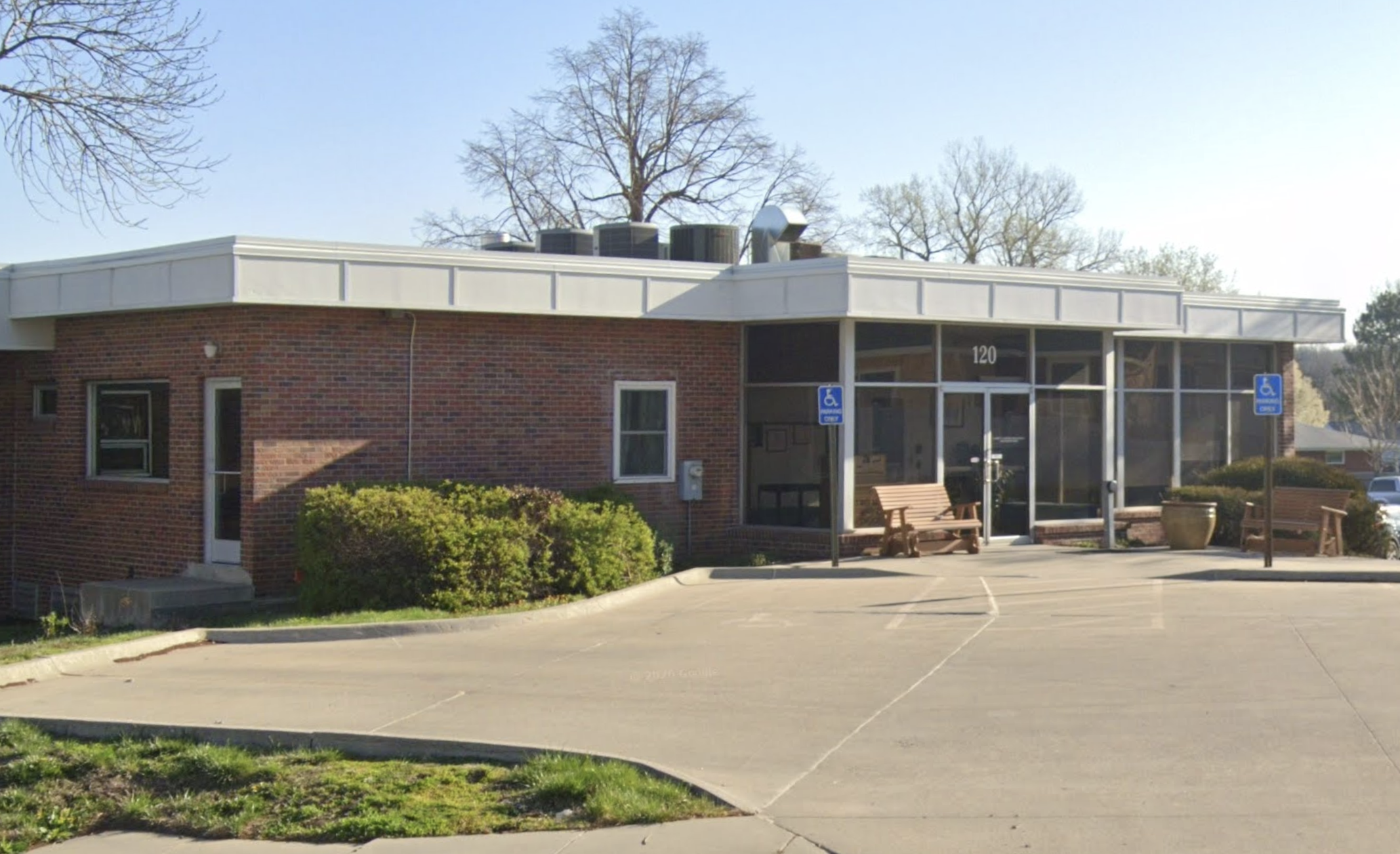 Single-story brick building with glass entrance and benches