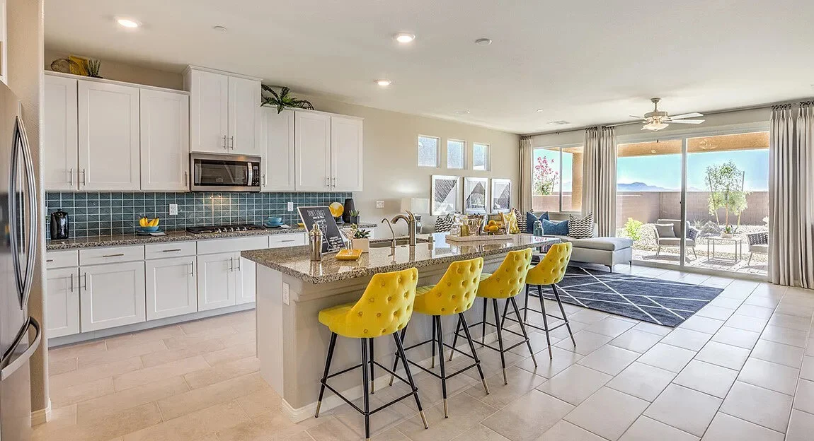 Bright modern kitchen with white cabinetry, large island, bar seating, and adjoining living area