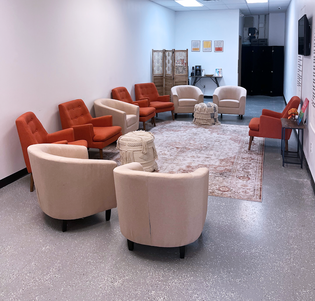 Group therapy room with orange and beige chairs in a circle.