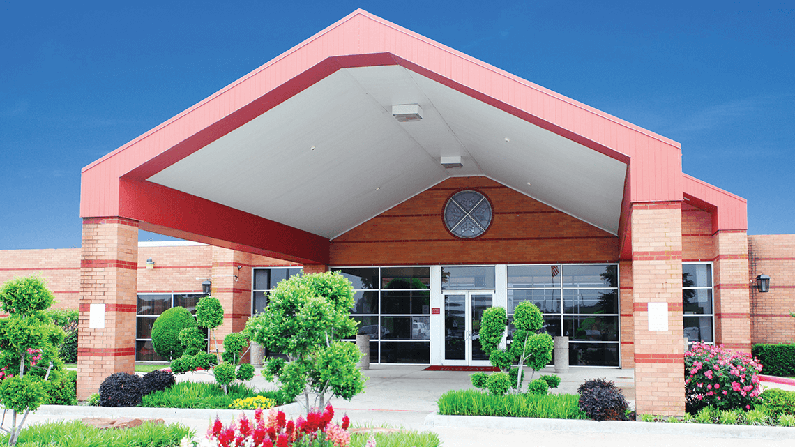 Main hospital entrance with landscaped grounds and flowers