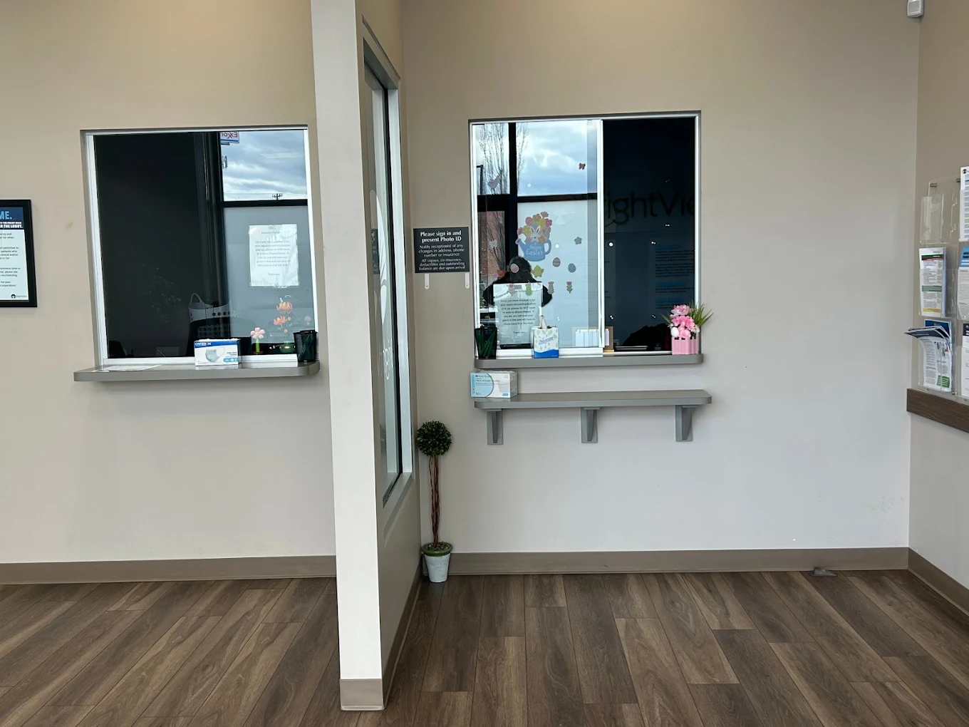 BrightView Health Winchester patient service area with two secure service windows, informational displays, seating, and wall-mounted television