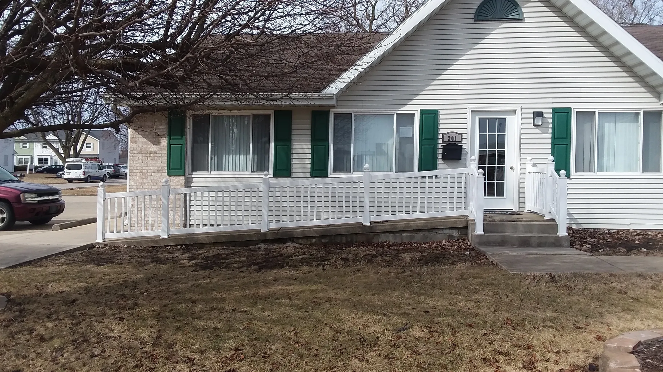 Small rehab center with ramp and white fencing.