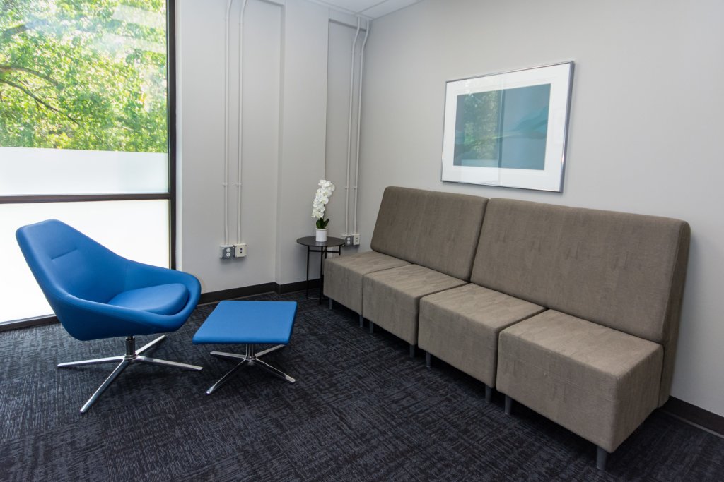  A lounge area with a blue chair and gray seating.
