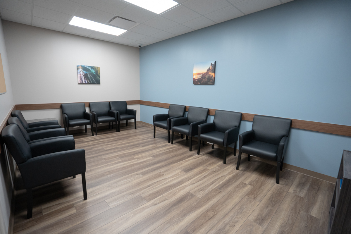 Dosing room with black chairs arranged along blue walls