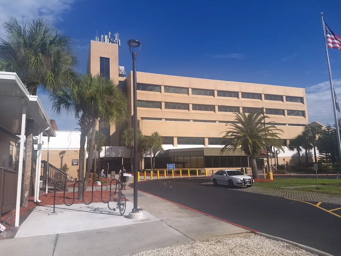 Exterior of a beige clinic with palm trees and a U.S. flag