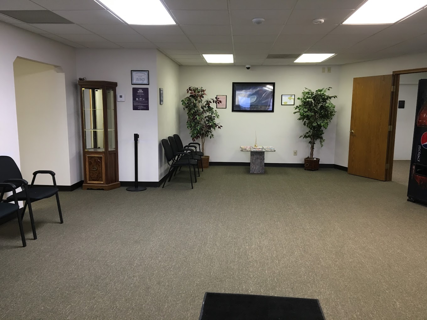 A waiting area with chairs, plants, and a glass display cabinet.