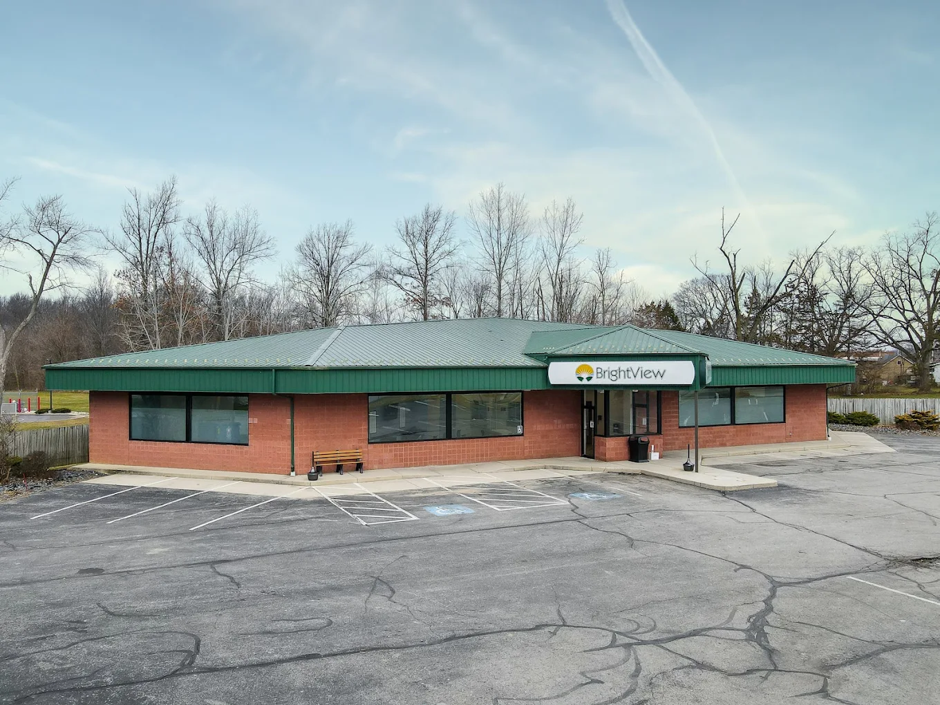 Exterior of BrightView Health in Lima, Ohio, showing the brick treatment center with green metal roof, BrightView entrance sign, parking lot, and accessible parking spaces