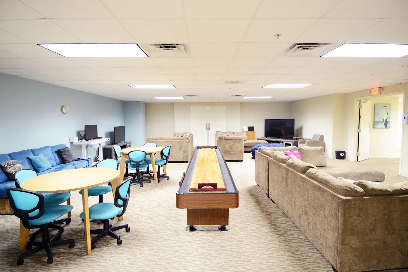 Recreation room with shuffleboard, sofas, tables, and TV