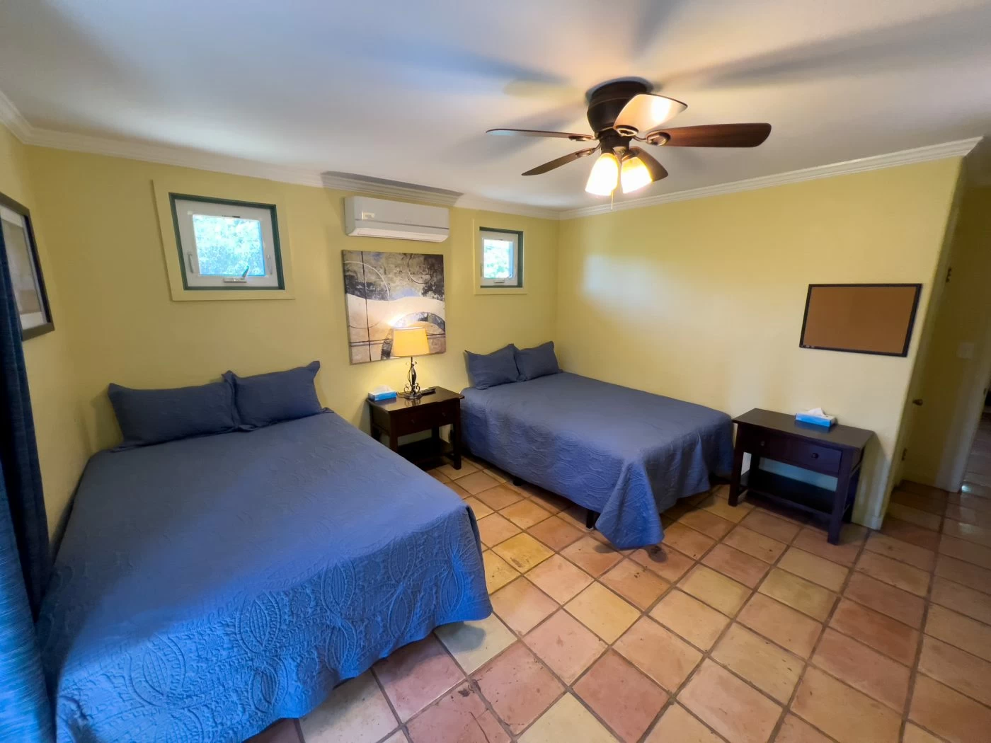 Room with two beds, blue bedding, and bedside tables