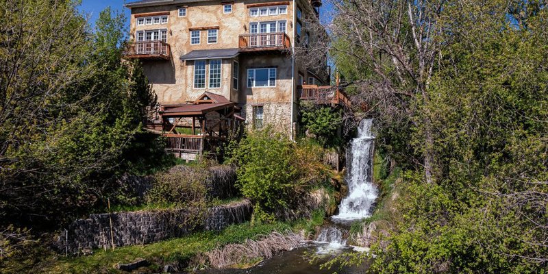  Charming stone building nestled in lush greenery with a cascading waterfall, creating a tranquil and scenic atmosphere perfect for relaxation.