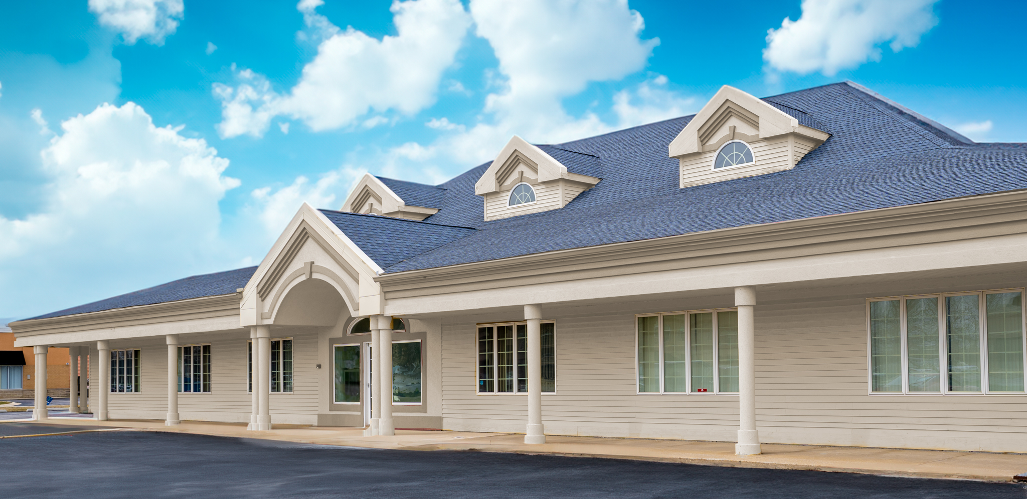 Single-story building with columns and blue roof under a bright sky.