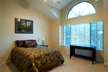 Bedroom with queen bed and large arched window