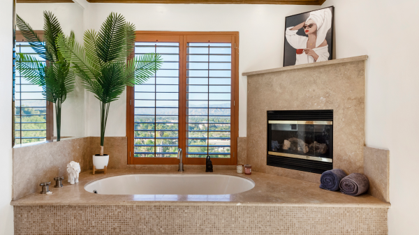 Luxurious bathroom with built-in bathtub, fireplace, and large window with scenic view