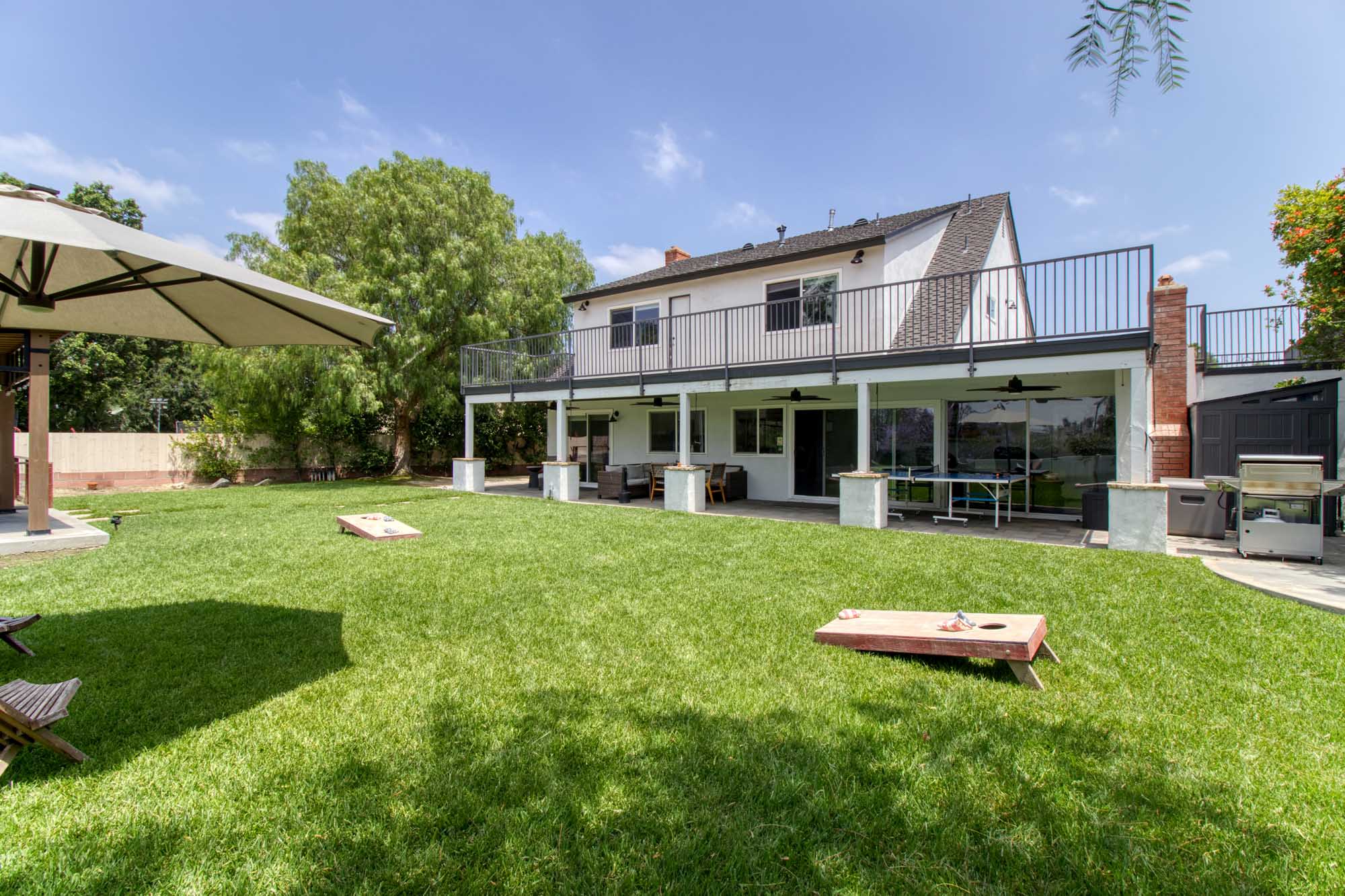 Large grassy yard with patio seating and outdoor games