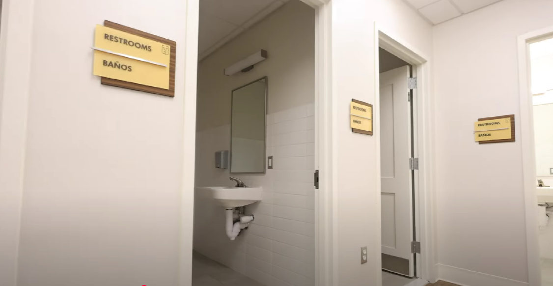 Hallway with restroom entrances and wall-mounted signs