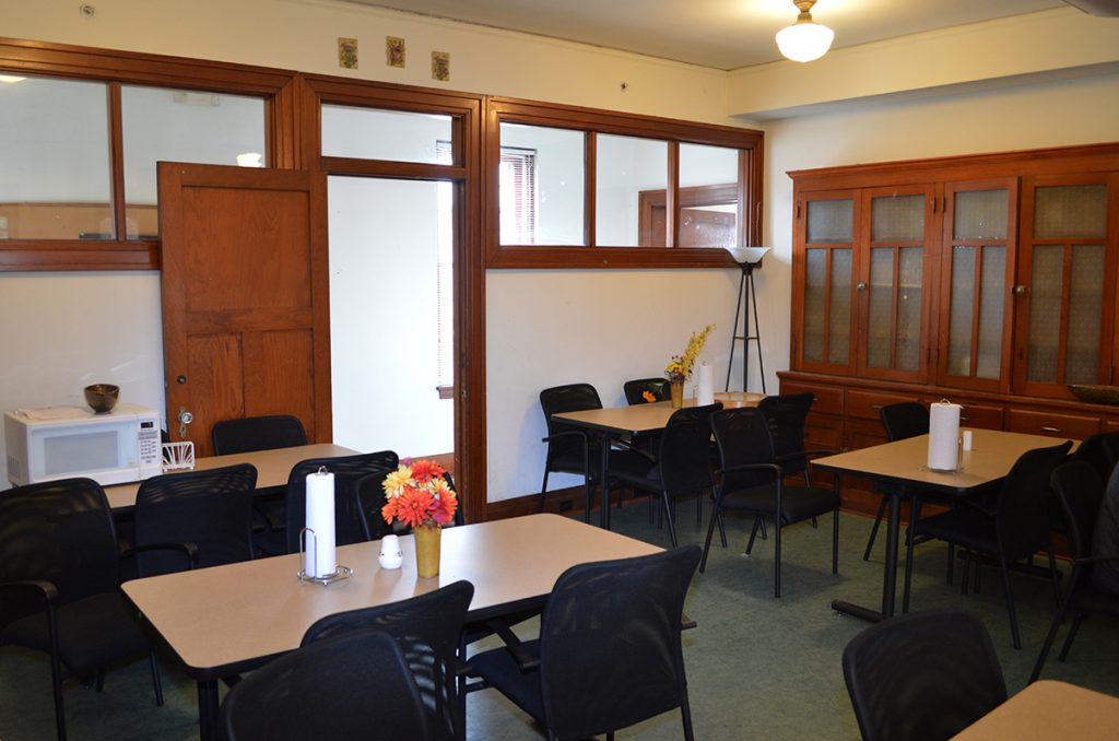 Dining area with tables, chairs, and wood cabinets along the wall