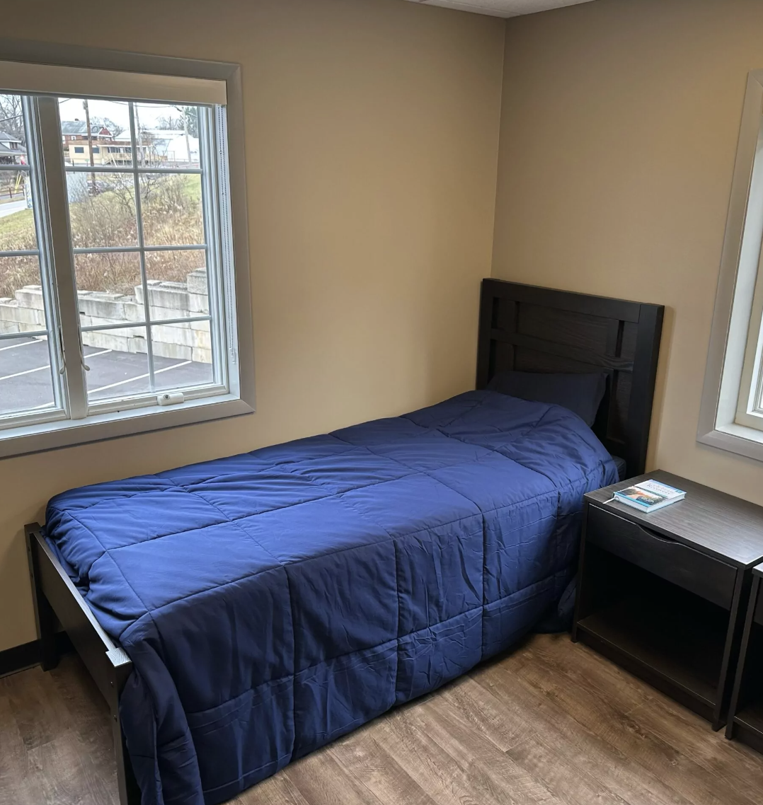 Private bedroom with single bed, nightstand, and large window.