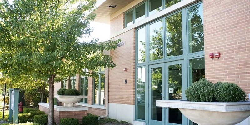  A modern brick building with large windows, surrounded by well-maintained greenery and trees, offering a bright and inviting exterior.