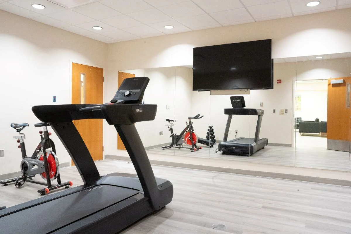 Gym with treadmill, exercise bike, and wall-mounted TV