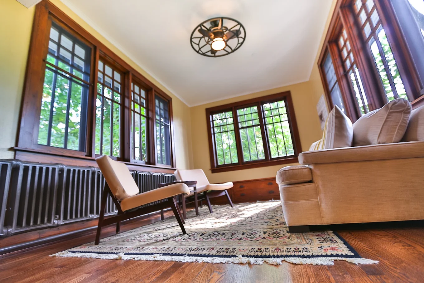 Bright sunroom lounge with seating and large wood-framed windows