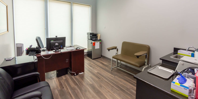 A clean, organized medical office with a desk, examination chair, and medical equipment, offering a professional and private setting for patient consultations.