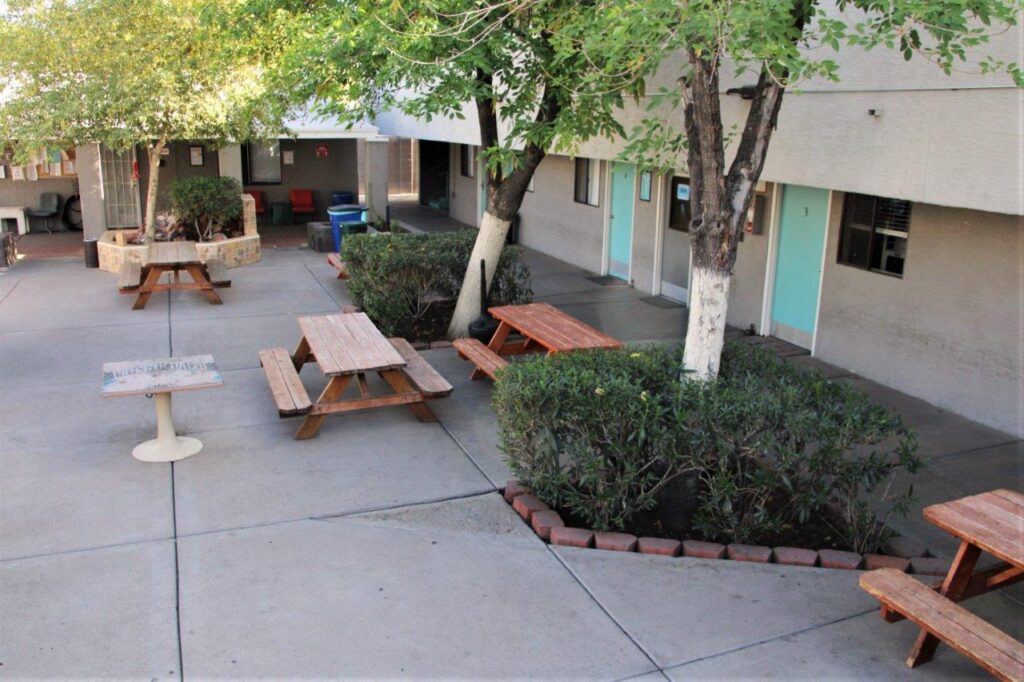Courtyard with picnic tables, trees, and rooms with turquoise doors