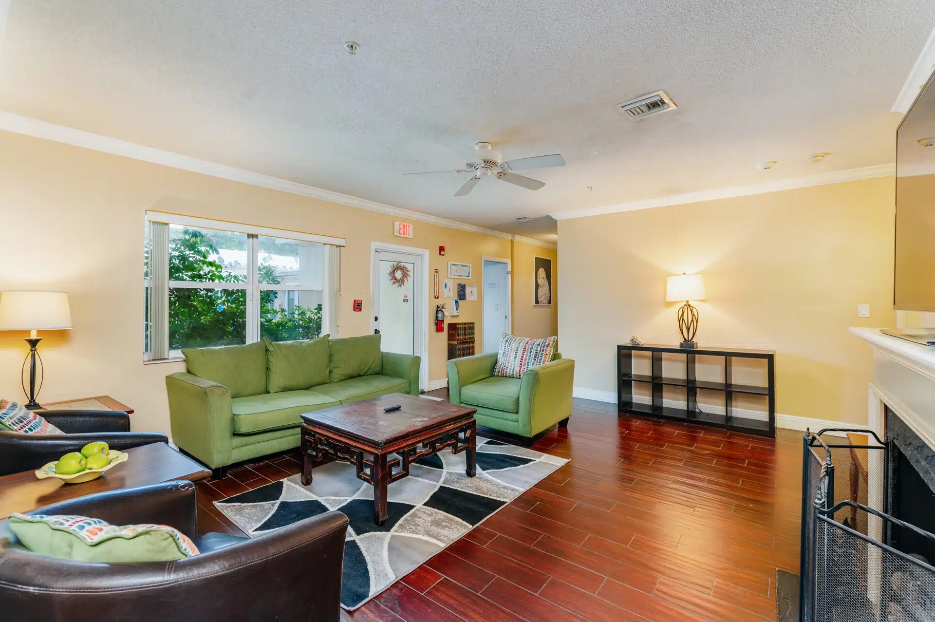Bright lounge with green sofas, wood floor, and a coffee table