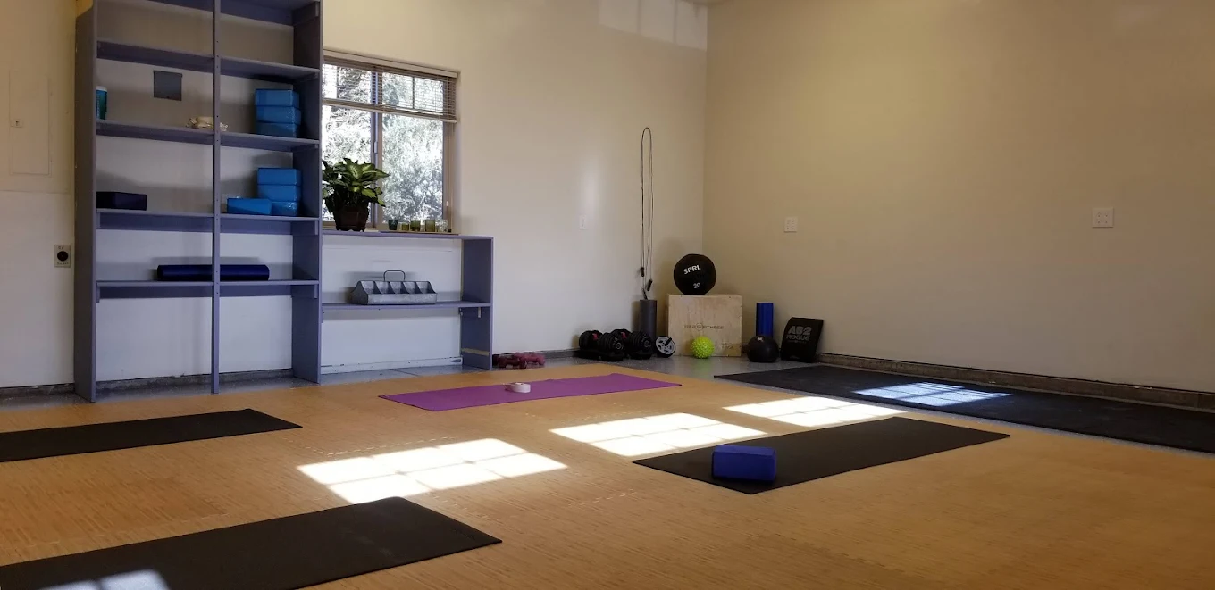 Yoga mats and fitness gear in sunlit exercise room