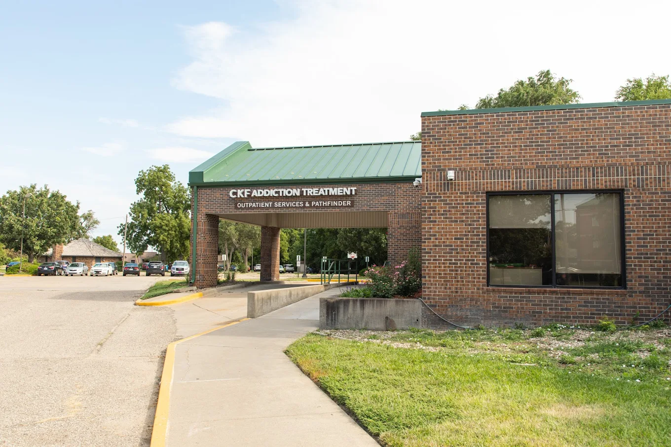 Brick building with green roof entrance labeled CKF Addiction Treatment