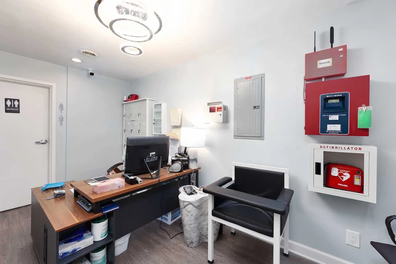 Clinical room with desk, patient chair, and medical equipment